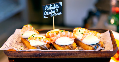 Obraz premium Appetizing spanish tapas with anchovies and shrimp close-up in the restaurant of San Sebastian, Donostia, Spain