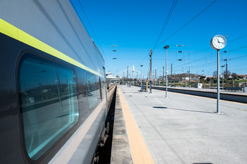 Beautiful railway station with modern commuter train at sunny day. Railroad outdoor platform