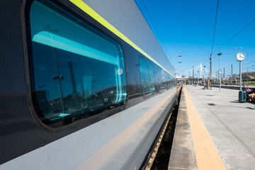 Naklejka na ściany i meble Beautiful railway station with modern commuter train at sunny day. Railroad outdoor platform