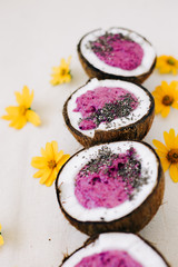 a plates of natural coconut shell with a healthy Breakfast green buckwheat smoothie with berries and Chia seeds and yellow flowers