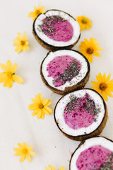 Obraz na płótnie Canvas a plates of natural coconut shell with a healthy Breakfast green buckwheat smoothie with berries and Chia seeds and yellow flowers