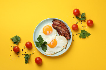 Delicious breakfast or lunch with fried eggs on yellow background, top view