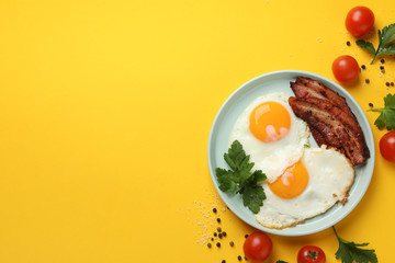 Delicious breakfast or lunch with fried eggs on yellow background, top view