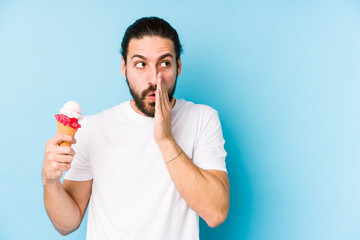 Young caucasian man eating an ice cream isolated is saying a secret hot braking news and looking aside