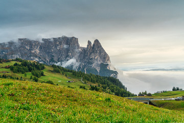 Fototapeta na wymiar Dolomites mountain landscape cover with low cloud in autumn in Alpe di siusi, Italy