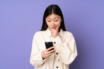 Young asian woman isolated on purple background thinking and sending a message