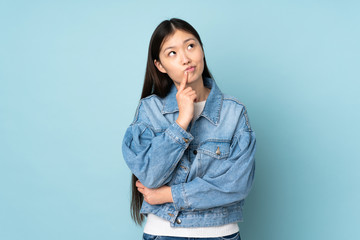 Young asian woman isolated on background having doubts while looking up