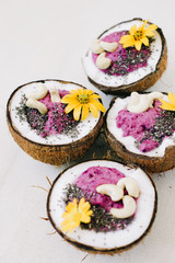 healthy Breakfast berry smoothie with Chia seeds and cashew nuts in a natural coconut plate decorated with yellow flowers on a white table