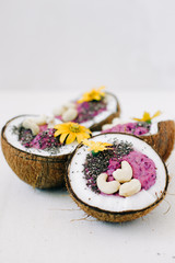 Fototapeta na wymiar healthy Breakfast berry smoothie with Chia seeds and cashew nuts in a natural coconut plate decorated with yellow flowers on a white table
