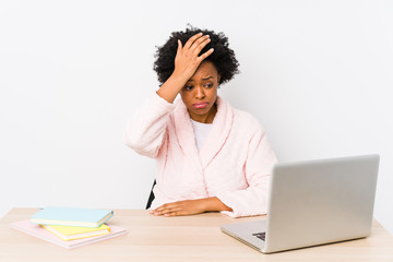 Middle aged african american woman working at home isolated being shocked, she has remembered important meeting.