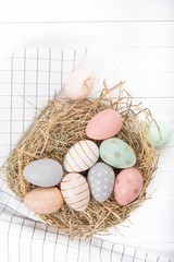 Easter table setting, holiday table home decor idea, flat lay composition with white plates, cutlery, colorful pastel painted Easter eggs, festive decor and fresh spring flowers