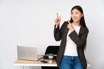 Business asian woman in her workplace isolated on white background pointing with the index finger a great idea