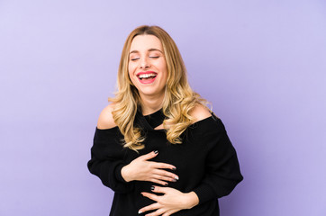 Obraz premium Young blonde woman isolated laughs happily and has fun keeping hands on stomach.