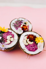 healthy Breakfast berry smoothie with Chia seeds and cashew nuts in a natural coconut plate on a pink table with colorful flowers