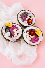 healthy Breakfast berry smoothie with Chia seeds and cashew nuts in a natural coconut plate on a pink table with colorful flowers