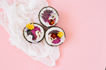 healthy Breakfast berry smoothie with Chia seeds and cashew nuts in a natural coconut plate on a pink table with colorful flowers