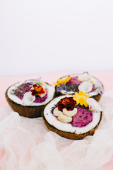 healthy Breakfast berry smoothie with Chia seeds and cashew nuts in a natural coconut plate on a pink table with colorful flowers