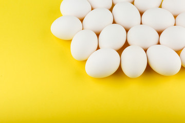 white eggs on yellow background top view with copy space
