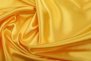 yellow satin fabric with creases. golden fabric texture