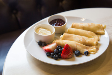 rolls of pancakes with cottage cheese decorated with blueberries and strawberries
