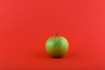green apple on red background with copy space