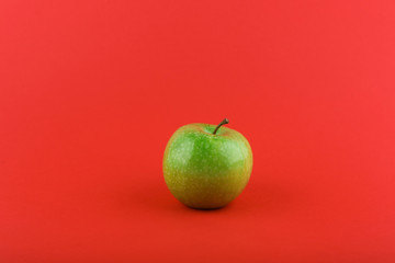 green apple on red background with copy space