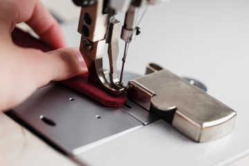 A leather craftsman produces leather goods on a sewing machine in his shop.