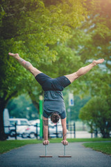 Uomo atletico che fa un esercizio di verticale durante un allenamento all'aperto nel parco