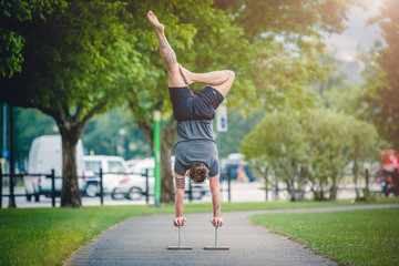 Uomo atletico che fa un esercizio di verticale durante un allenamento all'aperto nel parco © phRed
