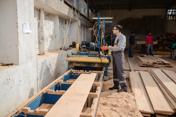 Fototapeta premium Young man carpenter at the wooden sawmill