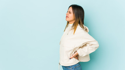 Young woman isolated on blue background suffering a back pain.