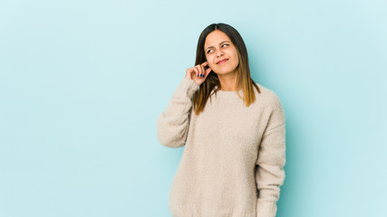 Young woman isolated on blue background covering ears with fingers, stressed and desperate by a...