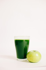 green freshly squeezed juice of green Apple and young spinach leaves on a white background