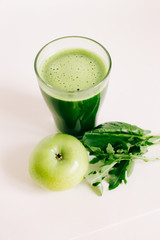 green freshly squeezed juice from green Apple and young beet leaves on a white background