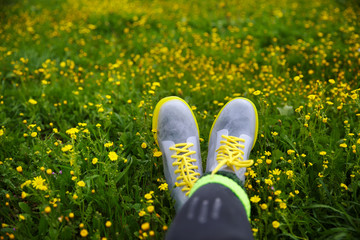 silicone shoes with yellow laces against meadows with green grass and yellow flowers