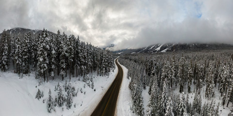 Aerial Panoramic Drone View of a beautiful Snow Covered Valley and a Scenic Road in Canadian Mountain Landscape during a cloudy winter day. Taken near Pemberton, British Columbia, Canada. Panorama