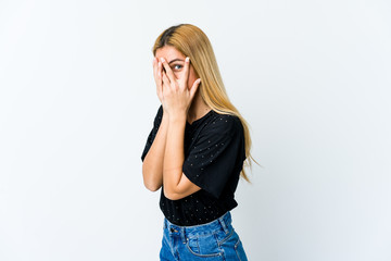 Young blonde woman isolated on white background blink through fingers frightened and nervous.