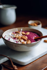 Purple berry smoothie with coconut flakes, oats and almond nuts.