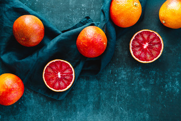 Flat lay food composition with blood oranges on a dark blue background.