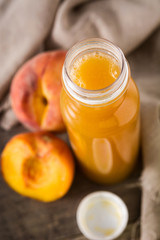 Natural peach juice in a bottle on wooden table