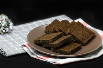 Brown bread on a plate, isolated on a black background.