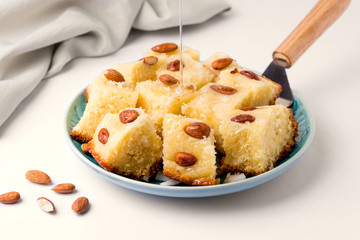 arabic sweet mannik of Basbus cut into slices in a plate on a light background