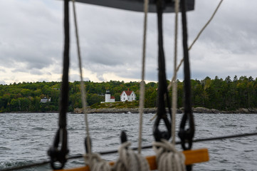 Obraz premium Lighthouse seen through ship rigging