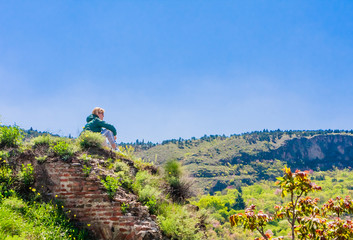 Tourist looking down who climbed ruins at Narikala- an ancient fortress overlooking the capital of...