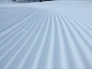 Snow velvet close up on ski slope. Prepared ski and snowboard track with trace of snow groomer on snow.