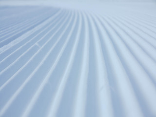 Snow velvet close up on ski slope. Prepared ski and snowboard track with trace of snow groomer on snow.