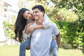 Naklejka premium happy young woman piggy back on man back at park