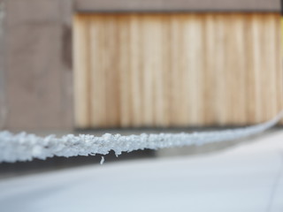 A rope covered with hoarfrost on the background of a wooden barn.