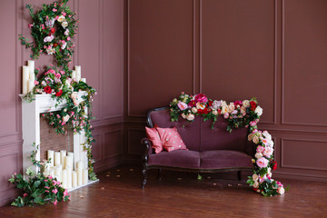 Decorated vintage room in natural style with a lot of flowers. Sofa, braided and twined with flowers.