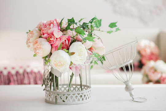 Decoration for wedding party in romantic vintage style.  Decorative cell with gentle pink flowers on a white table